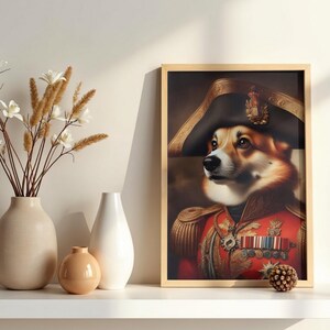 May include: A framed print featuring a Corgi dog in a red military jacket and a black bicorne hat. The artwork has gold detailing and medals. The background is dark and blurred. The frame is light brown.