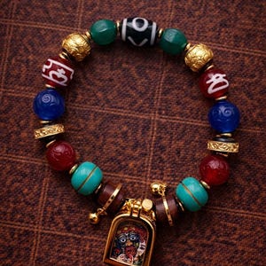 Puede incluir: Una colorida pulsera de cuentas con cuentas rojas, azules, verdes y doradas. La pulsera incluye un colgante con una imagen detallada. La pulsera tiene aproximadamente 18 cm de circunferencia.