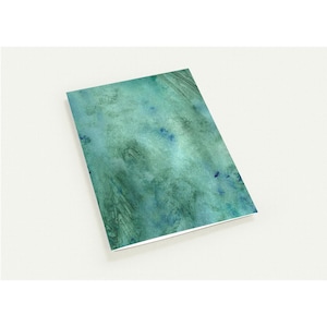 Puede incluir: Un cuaderno rectangular con un diseño de acuarela turquesa y azul. La cubierta presenta un patrón abstracto texturizado con diferentes tonos de turquesa y azul, creando un efecto marmolado. El cuaderno está sobre un fondo blanco.