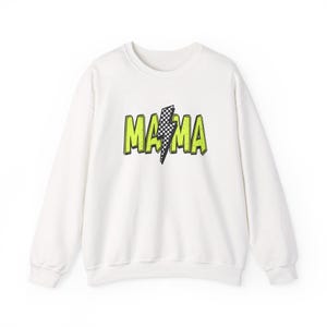 May include: White sweatshirt with the word "MAMA" in neon green block letters, with a black and white checkered lightning bolt graphic. The sweatshirt has long sleeves and a crew neck.