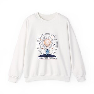 Könnte beinhalten: Weißes Sweatshirt mit einer Grafik eines Astronauten in einer Glühbirne, umgeben von Planeten und Linien. Der Text "COSMIC PROBLEM SOLVER" befindet sich darunter. Das Sweatshirt hat lange Ärmel und einen Rundhalsausschnitt.