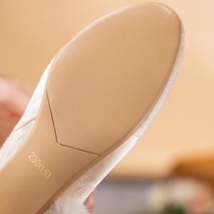 Peut inclure: La semelle d'une chaussure blanche pr&eacute;sentant une surface beige textur&eacute;e avec un motif &agrave; points fins. La semelle porte l'inscription 230(1.5). Le dessus de la chaussure est recouvert d'un tissu blanc &agrave; motif tonal et d'une bordure en fausse fourrure.