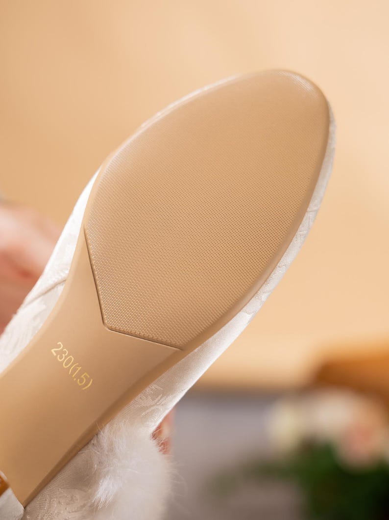 Peut inclure: La semelle d'une chaussure blanche pr&eacute;sentant une surface beige textur&eacute;e avec un motif &agrave; points fins. La semelle porte l'inscription 230(1.5). Le dessus de la chaussure est recouvert d'un tissu blanc &agrave; motif tonal et d'une bordure en fausse fourrure.