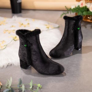 Peut inclure: Une paire de bottines noires avec un motif floral jacquard subtil, une bordure en fausse fourrure noire le long de l'ouverture sup&eacute;rieure et une perle verte unique sur la fermeture lat&eacute;rale. Les bottines ont un bout rond et un talon bloc.