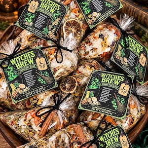 May include: Multiple clear plastic bags filled with a Witches Brew simmer pot blend, each featuring a black tag with green text and illustrations. The contents include dried orange slices, cinnamon sticks, cloves, and dried apple pieces, with a net weight of 1.5 oz.