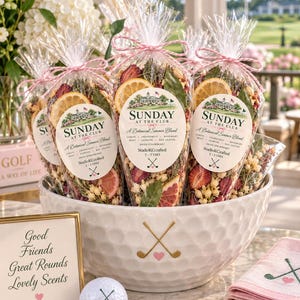 May include: Clear plastic cones filled with dried botanical simmer blend, featuring lemon slices, strawberries, and herbs. Each cone has a label reading Sunday at the Club, A Botanical Simmer Blend, StudioKCrafted, 2-3 uses, and a golf club icon.