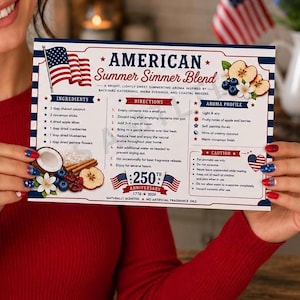 May include: A card for an "American Summer Simmer Blend" with a patriotic theme. The card features an American flag, ingredients, directions, and aroma profile. The card is held by a person with red, white, and blue nail polish.