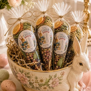 May include: A ceramic bowl shaped like a rabbit, filled with four cone-shaped clear bags containing dried flowers, herbs, and orange slices. Each bag has a label reading Happy Easter with a rabbit illustration. Speckled eggs sit near the bowl.