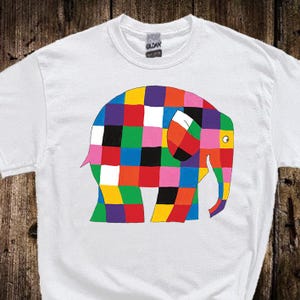 Peut inclure: T-shirt blanc avec un motif d'éléphant coloré en patchwork. L'éléphant est composé de carrés multicolores. Le t-shirt a un col rond et des manches courtes. Le design est attrayant et ludique.