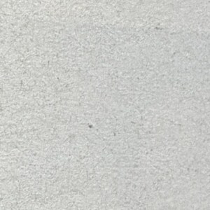 May include: A close-up shot of a light gray, textured surface. The surface has a slightly rough appearance, with subtle variations in tone and texture. The overall impression is of a solid, uniform material.