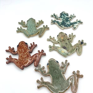May include: Five ceramic frog figurines in various colors, including green, brown, and blue. The frogs are in a playful pose with outstretched limbs, and each has a unique glaze pattern. These decorative frogs are ideal for home decor.
