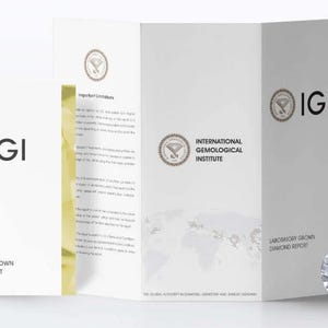 Op de afbeelding: Een witte brochure en een diamant worden gepresenteerd tegen een witte achtergrond. De brochure toont het IGI-logo en tekst, waaronder "Laboratory Grown Diamond Report". De diamant is rond en facetgeslepen. De brochure is open en toont meer tekst.