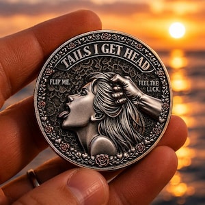 Può includere: Una moneta color argento con le parole "TAILS I GET HEAD" in un design circolare. La moneta presenta il profilo di una donna e una mano che le tocca i capelli. La moneta ha anche le frasi "FLIP ME" e "FEEL THE LUCK."