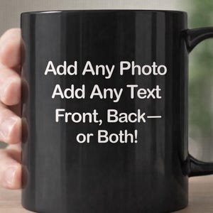 Może przedstawiać: Czarny kubek do kawy z białym tekstem „Add Any Photo, Add Any Text, Front, Back—or Both!”. Kubek ma zakrzywiony uchwyt i jest trzymany przez osobę.