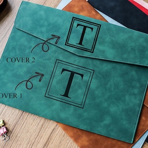 May include: A teal-colored document folder with a flap closure, featuring a large black letter "T" within a square frame. The text "COVER 1" and "COVER 2" are visible. Other folders in brown, black, and blue are partially visible.