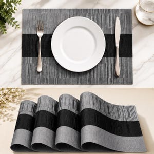 Puede incluir: Un mantel individual gris y negro con un plato blanco, un tenedor y un cuchillo. El mantel individual tiene un diseño texturizado con una franja negra en el centro. La imagen inferior muestra los manteles individuales enrollados.