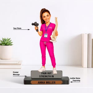 May include: A custom figurine of a healthcare professional in a bright pink scrub set, holding a black massage gun and a white anatomical spine model. The figure stands on a rectangular base with a gray plaque reading PAIN OUT STRENGTH IN.