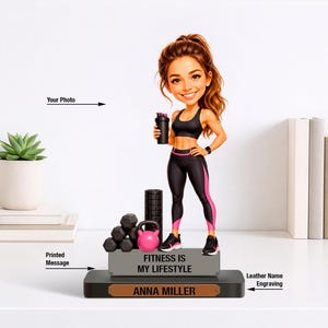 May include: A figurine of a woman in workout attire, holding a shaker bottle. The base features weights, a kettlebell, and the text "Fitness is my lifestyle." The name "Anna Miller" is engraved on a leather-like plaque.