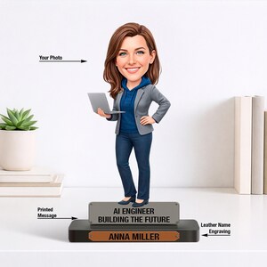 Può includere: Statuetta personalizzata di una donna con un laptop, vestita con una felpa con cappuccio blu, un blazer grigio e jeans. La base presenta il testo "AI ENGINEER BUILDING THE FUTURE" e il nome "ANNA MILLER".
