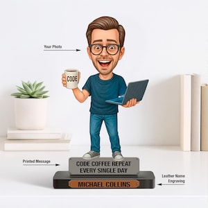 Könnte beinhalten: Eine Figur eines Mannes, der einen Laptop und eine Kaffeetasse mit dem Wort "CODE" darauf hält. Der Sockel trägt den Text "CODE COFFEE REPEAT EVERY SINGLE DAY" und "MICHAEL COLLINS". Der Mann trägt eine Brille, ein blaues T-Shirt und Jeans.