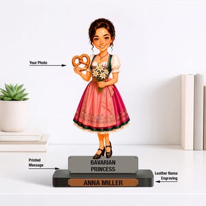 May include: A custom figurine of a girl in a traditional Bavarian dress holding a pretzel and flowers. The base features a grey plaque with the text BAVARIAN PRINCESS and a brown leather plaque with the engraved name ANNA MILLER.