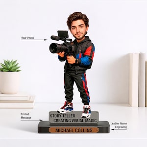 May include: A figurine of a person holding a video camera, wearing a black jacket with red and blue accents, and black pants with red stripes. The base reads "STORY TELLER CREATING VISUAL MAGIC" and "MICHAEL COLLINS".