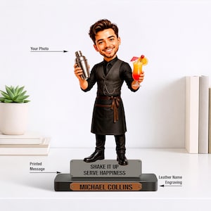 May include: A custom bobblehead figurine of a bartender wearing a black waistcoat, shirt, and apron. The figure holds a silver cocktail shaker and a tropical drink. The base features a grey plaque with the text SHAKE IT UP SERVE HAPPINESS and a brown leather nameplate with MICHAEL COLLINS.