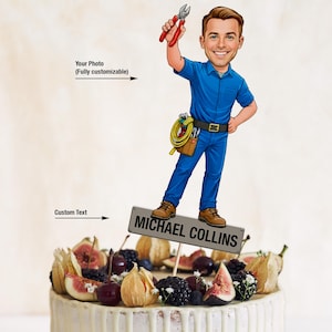 May include: A cake topper featuring a cartoon illustration of a smiling man in blue work clothes holding pliers. The man stands on a sign that reads "MICHAEL COLLINS". The cake is decorated with fruit and cream.