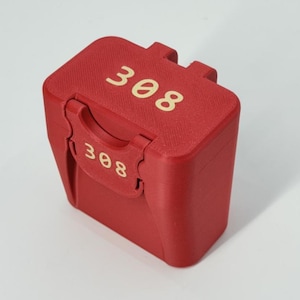 May include: A red, rectangular container with the number "308" printed in gold on the top and front. The container has a textured surface and a hinged lid with a latch. The background is plain white.