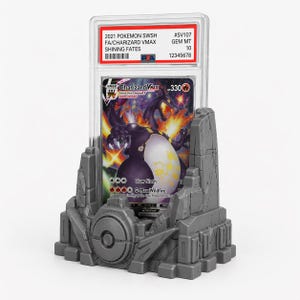 May include: A graded Pok&eacute;mon card featuring Charizard VMAX, displayed in a clear case. The card is set in a gray, stylized stone display stand. The card's details include the text "2021 POKEMON SWSH FA/CHARIZARD VMAX SHINING FATES".