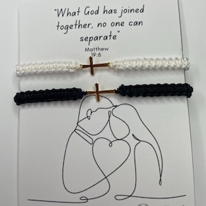 May include: Two macrame bracelets, one white and one black, each with a gold-coloured cross charm. The bracelets are displayed on a card with the text "What God has joined together, no one can separate" and a line drawing of a couple.