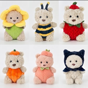 May include: Six plush teddy bears in various costumes. One is a sunflower, another a bee, and a third a strawberry. The others are a pumpkin, a peach, and a cat. Each bear has a light brown fur and a stitched nose and eyes.
