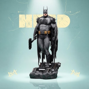 Puede incluir: Estatua detallada de Batman con un traje gris y negro, sosteniendo un arma. La figura se alza sobre una base rocosa con un diseño texturizado. El fondo es de color verde azulado claro con la palabra "HID" en un rectángulo amarillo.