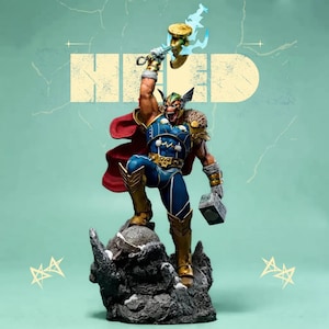 Op de afbeelding: Een gedetailleerd beeldje van Thor, de Marvel Comics-superheld, in een dynamische pose. Hij draagt een blauw en goud kostuum, een rode cape en houdt een hamer omhoog met bliksemeffecten. De basis is een rotsformatie en de achtergrond is lichtgroen met het woord "NERD".