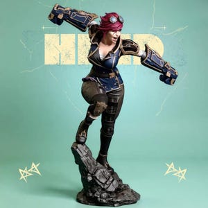 Puede incluir: Figura detallada de un personaje en pose dinámica, vistiendo un atuendo azul y negro con guanteletes mecánicos. La figura tiene pelo rojo y gafas, de pie sobre una base rocosa contra un fondo turquesa con la palabra "HIND" en el fondo.