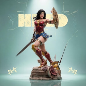 May include: A Wonder Woman statue in a dynamic pose, holding a sword and shield. The figure is clad in a red, blue, and gold costume, with a detailed base. The background features a stylized design and the word "HERO".