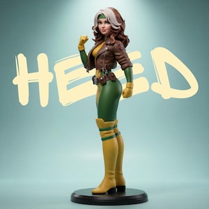 May include: A collectible figurine of a character with brown hair and a white streak, wearing a brown leather jacket, green bodysuit, and yellow gloves and boots. The figure stands on a black circular base with the text HEED in the background.