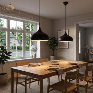 Könnte beinhalten: Zwei schwarze Pendelleuchten mit Holzakzenten hängen über einem Holzesstisch, der mit Tellern und Besteck gedeckt ist. Der Raum hat ein großes Fenster und eine neutrale Farbpalette, die eine warme und einladende Atmosphäre schafft.