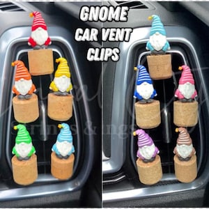 Könnte beinhalten: Bunte Zwerg-Autolüftungsclips. Jeder Zwerg hat einen andersfarbigen Hut und Bart und ist auf einem Korksockel befestigt. Der Text "GNOME CAR VENT CLIPS" ist in Weiß dargestellt.
