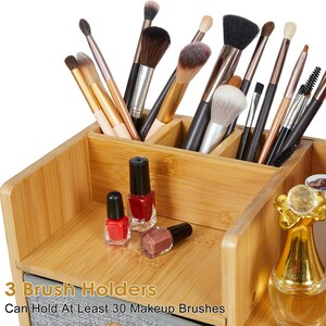 May include: A bamboo makeup organizer with multiple compartments containing various makeup brushes, three small nail polish bottles, and a gold-topped glass bottle. Text on the image reads: 3 Brush Holders, Can Hold At Least 30 Makeup Brushes.