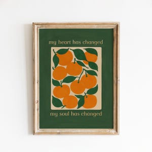 May include: A framed art print featuring a stylized illustration of oranges with green leaves on a beige background, set against a dark green backdrop. The text "my heart has changed" and "my soul has changed" are displayed on the print.