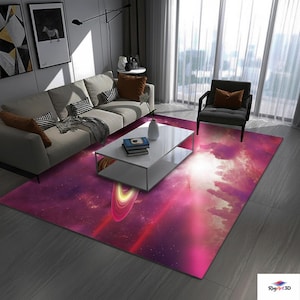 May include: A rectangular area rug with a vibrant space-themed design. The rug features a deep purple and pink color palette with a depiction of a planet with rings and a nebula. The rug is placed in a living room setting.