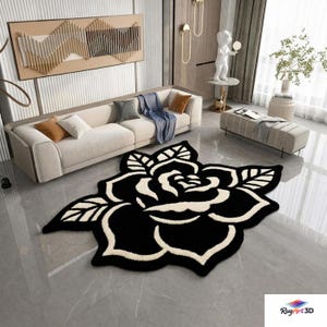 Puede incluir: Una alfombra negra y crema con forma de rosa sobre un suelo de baldosas grises. La alfombra es el punto focal de un salón moderno, con un sofá beige, cojines decorativos y obras de arte en el fondo. El diseño de la alfombra es un gran patrón floral.