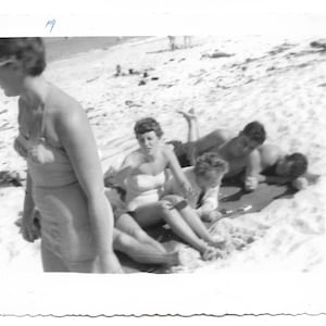 A Day At The Beach Vintage Snapshot Woman Wearing Swimsuit Walks Out Of Frame Friends On Beach Blanket Abstract Black & White Photo