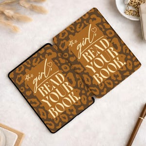 Op de afbeelding: Twee rechthoekige items met een bruine luipaardprint en de tekst "girl READ YOUR BOOK." De tekst is in een handschriftstijl met een ster en een hart. De items hebben een zwarte rand en liggen op een wit oppervlak.