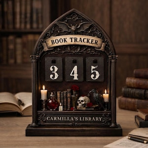 May include: A dark brown gothic-style book tracker with the text "BOOK TRACKER" and the numbers 345. The base features the text "CARMILLA'S LIBRARY" and includes candles, a skull, a raven, and miniature books.