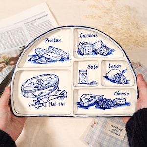 May include: A set of three ceramic mugs with a speckled, cream-colored glaze. Each mug features a different hand-painted floral design in shades of blue, green, and yellow. The mugs have a simple, rounded shape.