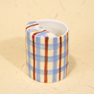 May include: A set of three ceramic mugs with a speckled, matte finish. The mugs are in shades of cream, light gray, and dark gray. Each mug has a simple, minimalist design and a rounded handle.