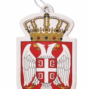Könnte beinhalten: Ein weißer, schildförmiger Lufterfrischer mit dem serbischen Wappen. Das Design umfasst einen doppelköpfigen Adler, eine Krone und einen rot-weißen Schild. Eine Schnur zum Aufhängen ist befestigt.