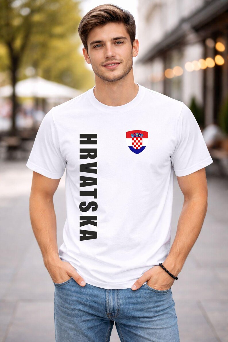May include: White t-shirt with the word "HRVATSKA" printed vertically in black on the left side. A Croatian coat of arms is on the right chest. The shirt is short-sleeved.
